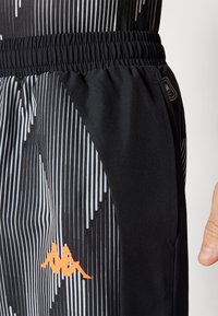 Zwarte sportshorts met een getextureerd patroon van witte verticale lijnen, een oranje logo-detail en een elastische tailleband voor comfort.