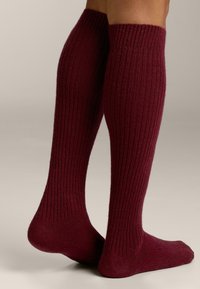 Knielange bordeauxrode sokken van geribbelde gebreide stof, met een aansluitende pasvorm, zachte textuur en verstevigde hiel en teen.
