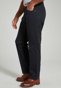 Navyblauwe katoenen broek in een blend met rechte benen, voorzakken en gedetailleerde stiksels. Draagt een paar bruine leren schoenen.