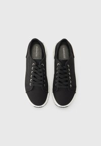 Svarte lerrets sneakers med hvite gummisåler. Funksjoner inkluderer rund tå, metallhjul og flate svarte snører. Enkel design.