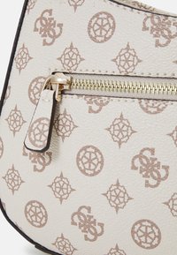 Ronde handtas van beige textiel met een lichtbruine geometrische patroon, een gouden rits en een ritssluiting aan de voorkant.