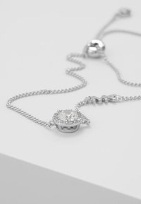 Collana in argento con ciondolo centrale rotondo circondato da pietre più piccole in una montatura circolare, dotata di un clasp a sfera liscia.