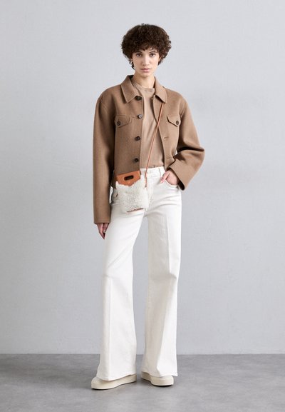 Brun uldjakke med store knapper, beige top, hvide vide bukser og en lille shearling crossover-taske med en brun rem. Glat tekstur.