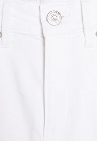 Tejido de mezclilla blanca con cierre de botón y detalles de costura. Textura suave con un diseño limpio y minimalista. Sin patrones visibles.