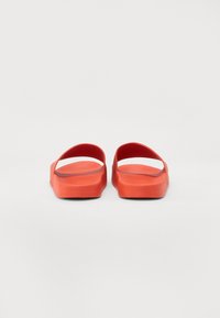 Chanclas de goma rojas con diseño abierto, que cuentan con suelas planas, correas anchas y una base texturizada para mayor comodidad.