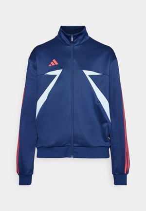 Marineblå atletisk jakke med høj krave, lynlåslukning, lyseblå detaljer og røde striber på ærmerne. Fremstillet af glat, strækbart stof.