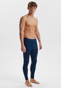 Marineblå lang undertøy med en tettsittende design, laget av myk stoff, med elastisk midjebånd og ribbestrikkede mansjetter ved anklene.