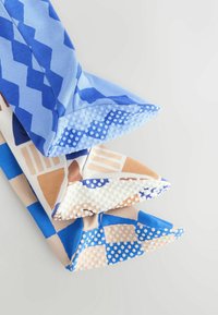 Tres calcetines de tela con patrones geométricos variados en azul, marrón y blanco, con acentos de goma texturizada en los extremos para mayor agarre.