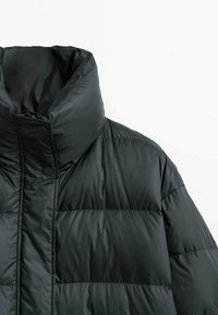 Sort højhalset dunjakke med trykknapper og horisontal quiltning på hvid baggrund.