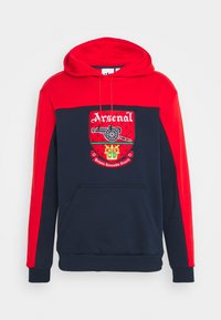 Röd och marinblå hoodie med en framficka, dragsko i huvan och en broderad Arsenal-logotyp på bröstet med detaljerade designelement.