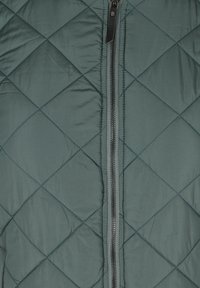 Gequiltigde groene vest met een voorkant rits, met een ruitpatroon en een gladde textuur. Zwarte rits trekker en stikdetails.