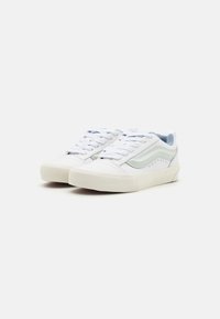 White canvas sneakers with light blue accents, flat laces, rounded toe, and a textured rubber sole. Features a simple side stripe design.