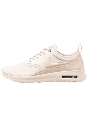 Beige Nike Air Max sneaker met een gestructureerd bovenwerk, zichtbare luchtvering in de zool, veters aan de voorkant en een trekbandje bij de hiel.