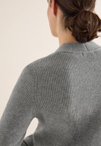 Grau gerippter Pullover mit tailliertem Design, featuring einen hohen Kragen und glatter Textur. Sichtbare Nähte entlang der Schultern.