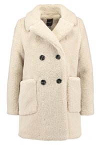Abrigo de piel sintética color crema, de doble botonadura, con amplio cuello y dos grandes bolsillos frontales, diseñado para mujeres.