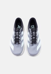 Ζευγάρι γκρι και λευκά αθλητικά παπούτσια τρεξίματος με μαύρα κορδόνια, σε θέαση από πάνω σε λευκό φόντο.