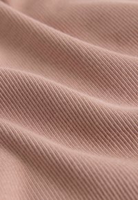 Tessuto morbido a coste in un colore rosa tenue, che mostra onde delicate e sottili variazioni di texture. Ideale per abbigliamento o rivestimenti.