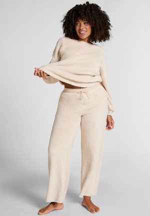 Fleece loungewear set in lichtbeige; lang - mouw top en wijdvallende broek met een elastische tailleband en trekkoord detail. Zachte textuur.