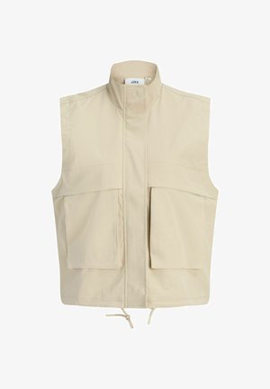 Beeživärviline varrukateta vest kõrge kraega, eesmine tõmblukk kaane all peidetud, kaks suurt esimest taskut ja reguleeritav paeläär.