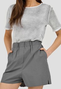 Jasnoszara, prążkowana koszulka z okrągłym dekoltem, w zestawie z szarymi szortami na elastycznej talii z bocznymi kieszeniami i luźnym krojem.