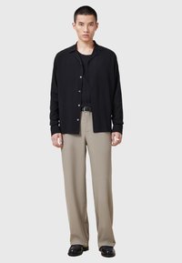 Zwarte button-up overhemd gemaakt van lichtgewicht stof, gecombineerd met beige wijde broek. De outfit heeft een eenvoudig ontwerp en een ontspannen pasvorm.