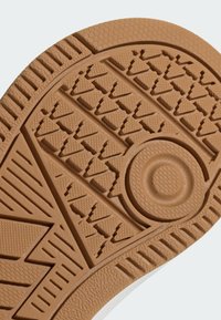 Podeszwa buta z beżowej gumy, z teksturowanym bieżnikiem o wzorze trójkątów i okrągłych akcentach zapewniających przyczepność.