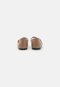 Brown leather flats with a smooth texture, low heel, and rounded toe, featuring a brown bow accent on the side.