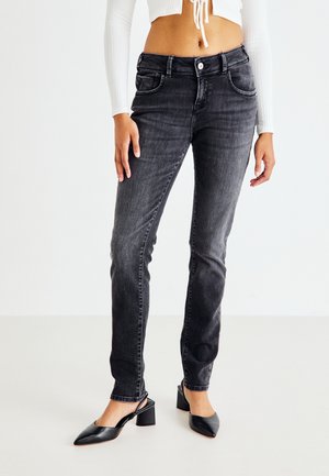 Black, slim-fit jeans with faded texture, five pockets, and a front button closure. Paired with black heeled shoes and a white crop top.