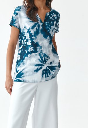 Haut en tie-dye bleu et blanc avec un décolleté en V et des manches courtes. Fait en tissu léger, il présente une coupe décontractée et un ourlet arrondi.