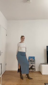 Dolga modra krila z stranskim razporkom, v kombinaciji z oprijetim belim topom z dolgimi rokavi in sijajnimi črnimi gležnjarji. Preprost, elegantno zasnovan.