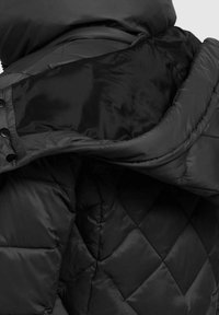 Chaqueta de plumas acolchada negra con tejido liso y brillante, cuello alto y botones visibles a lo largo de la tapeta. El interior presenta un forro en contraste.