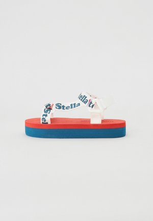 Colorful platform sandal with red upper, blue sole, and white straps featuring 'Stella' text. Made of durable rubber-like material, flat design.