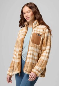 Fuzzy beige and white plaid jacket with a brown chest pocket, zip front, and soft texture, paired with a light blue top.