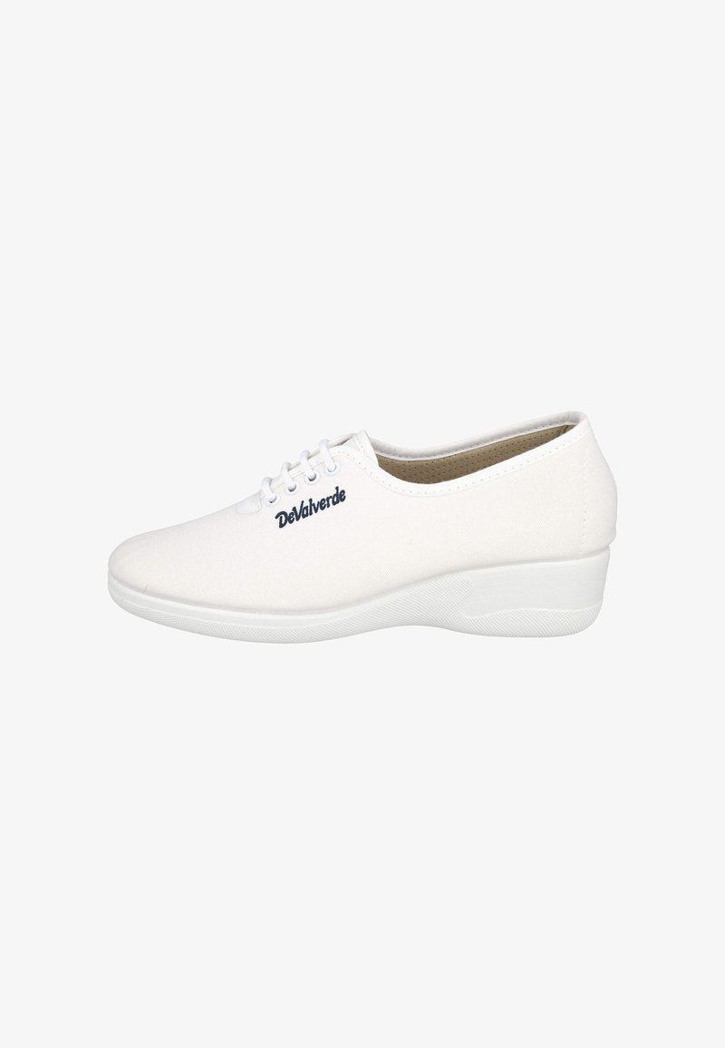 Zapatilla de lona blanca con punta redonda, un sutil patrón texturizado y una suela blanca elevada. Incluye cordones blancos y un logo decorativo en color marino.