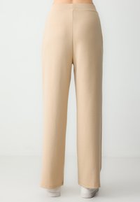 Beige wijde broek gemaakt van zachte, rekbare stof met een gladde textuur en een hoge tailleband, met een eenvoudig en strak ontwerp.