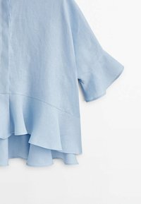 Haut en lin bleu clair avec un ourlet évasé, des manches courtes et un design simple et décontracté, présentant une texture douce et une coupe ample.