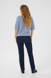 Pull en tricot bleu clair à manches courtes associé à un jean slim bleu foncé. Le jean présente des poches arrière et une coupe droite.