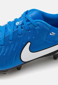 Blue athletic shoe featuring synthetic upper, textured detailing, black sole, white swoosh logo, and lace-up design. Suitable for soccer.