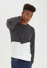 Gray and white pullover sweatshirt with long sleeves, featuring a cropped design and contrast color blocks across the chest. Soft texture.