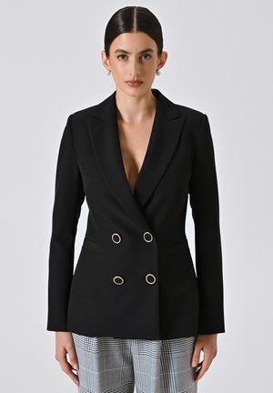 Blazer doppio petto nero con bottoni ovali dorati, colletto appuntito e vestibilità su misura, abbinato a pantaloni a quadri. Finitura in tessuto liscia.