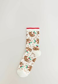 White sock with red cuff featuring brown Christmas pudding and green holly with red berries pattern on a beige spotted background.