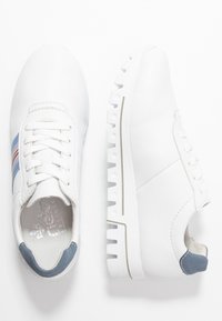 Sneakers bianchi con lacci, finitura testurizzata, caratterizzati da strisce blu e rosse, una suola spessa bianca con design seghettato e dettagli in blu uniforme.