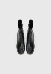 Schwarze Leder-Stiefeletten mit einem eleganten Design, ausgestattet mit einem seitlichen Reißverschluss, spitzem Schuhblatt und glatter Textur. Flacher Absatz für Stabilität.