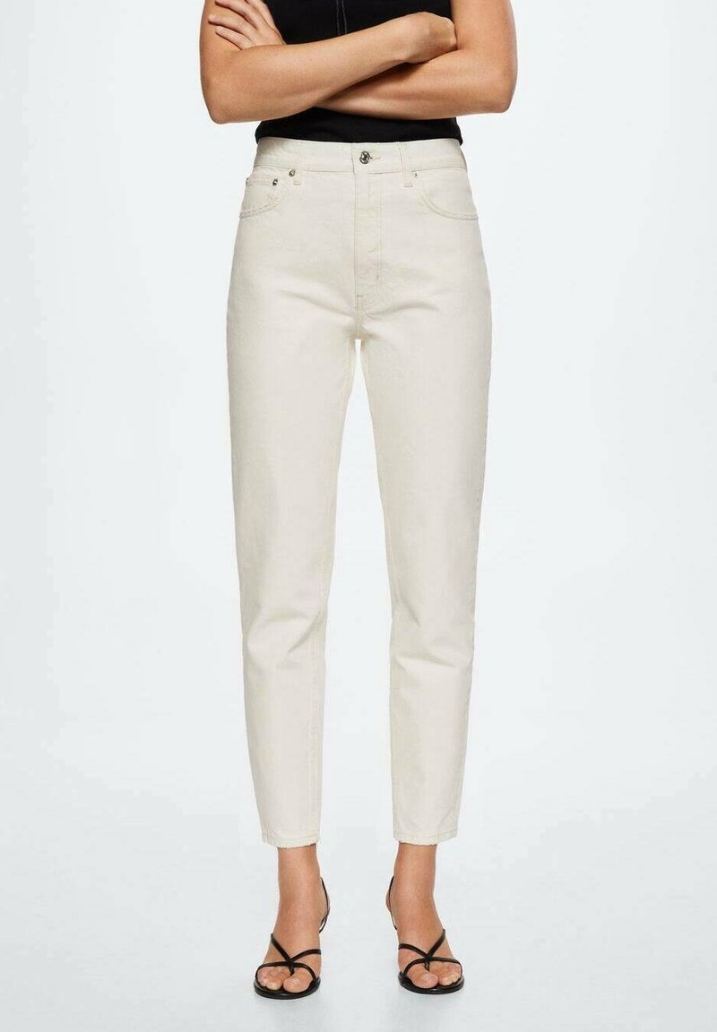 Jeans en denim couleur crème, à taille fuselée. Comprend des poches avant, une fermeture éclair et une texture lisse. Associés à des sandales noires.