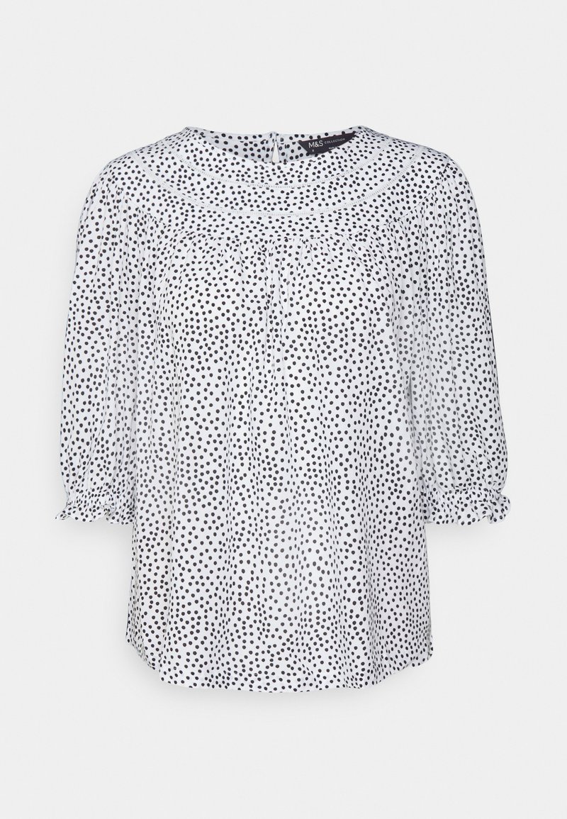 Blusa branca com bolinhas pretas, tecido translúcido, decote redondo, mangas 3/4 elásticas e pregas suaves para um ajuste descontraído.