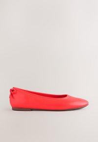 Roter flacher Ballettschuh mit abgerundeter Spitze und kleinem Schleifendetail an der Ferse, seitlich vor einfarbigem Hintergrund dargestellt.
