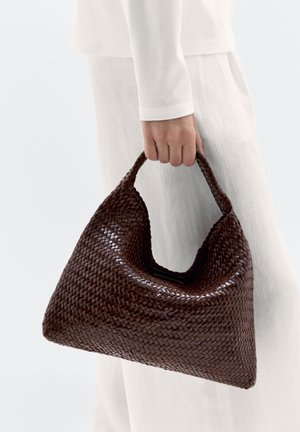 Sac à main tissé marron avec une forme triangulaire, une poignée courbée et une texture glossy. Le design présente des motifs entrelacés complexes.