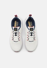 White sporty sneakers with mesh upper, navy lining, red accents, and white laces. Features memory foam insole and textured sole.