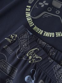 Tmavomodrá tkanina s potlačou herných ovládačov, klávesnice a myši a s nápisom "THE GAME BEGIN EVERY DAY IS A" svetložltej farby.