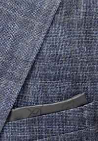 Blue textured blazer pocket with a gray patterned pocket square neatly folded inside.